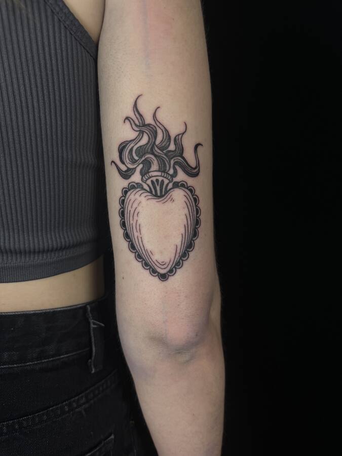 Cœur ardent couronné de flammes, tatoué à l'arrière du bras
