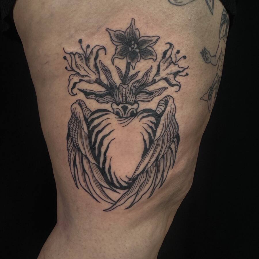 Cœur ailé surmonté de lys, tatoué sur une cuisse