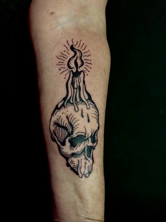 Crâne surmonté d'un cierge, tatoué sur un avant-bras