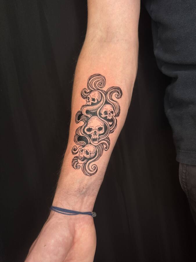 Crânes dans les nuages, tatoués sur un avant-bras