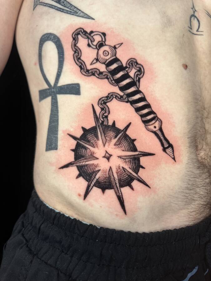 Masse d'armes enchaînée et croix ansée, tatouées sur le flanc