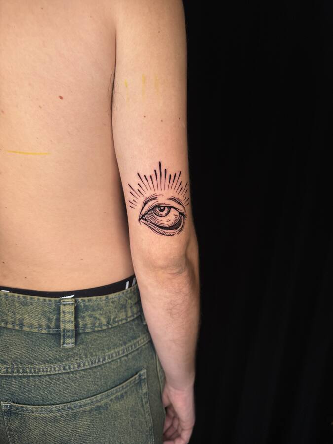 Œil rayonnant tatoué à l'arrière du coude, cicatrisé