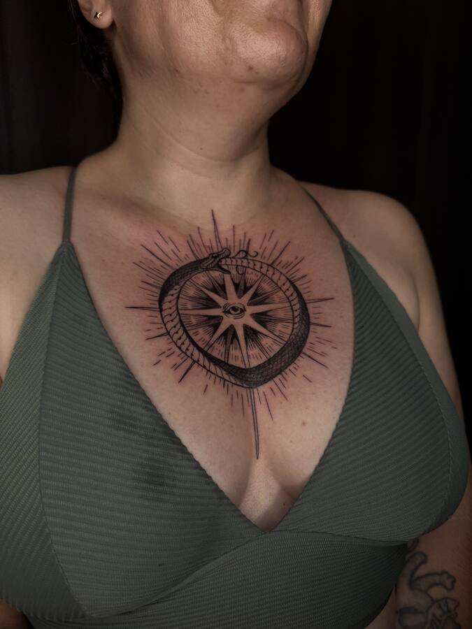Rose des vents cerclée d'un serpent, tatouée sur le sternum