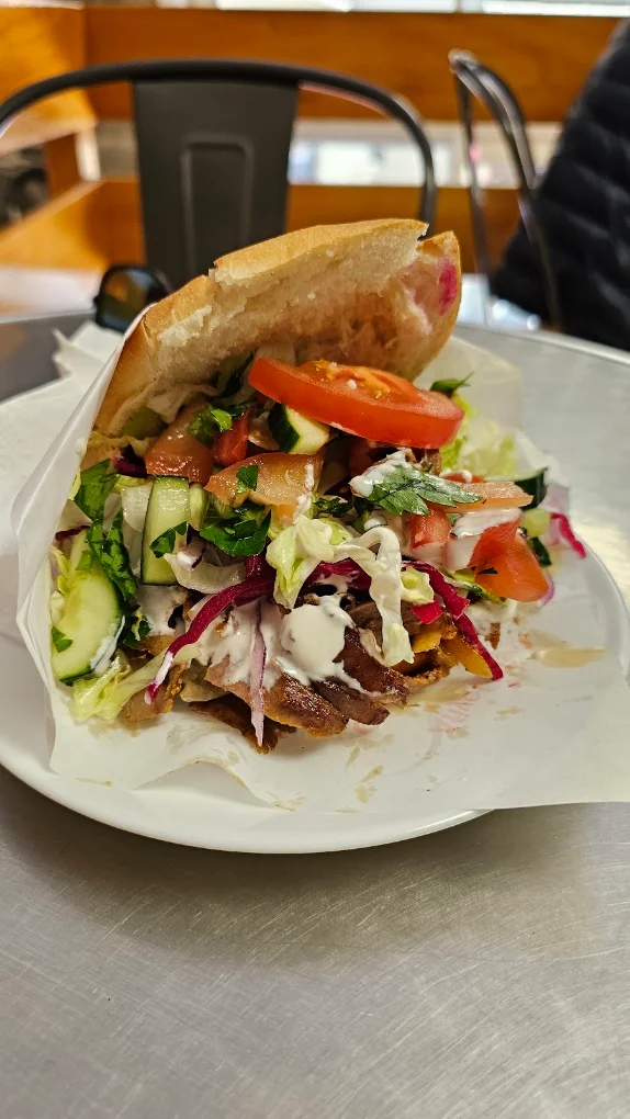 Un sandwich veau-agneau du Snack du Marché, tenu à la main